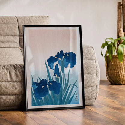 Poster of vibrant blue irises with green leaves on a gradient background artwork Blue Irises by Ohara Koson, framed and displayed in modern living room decor