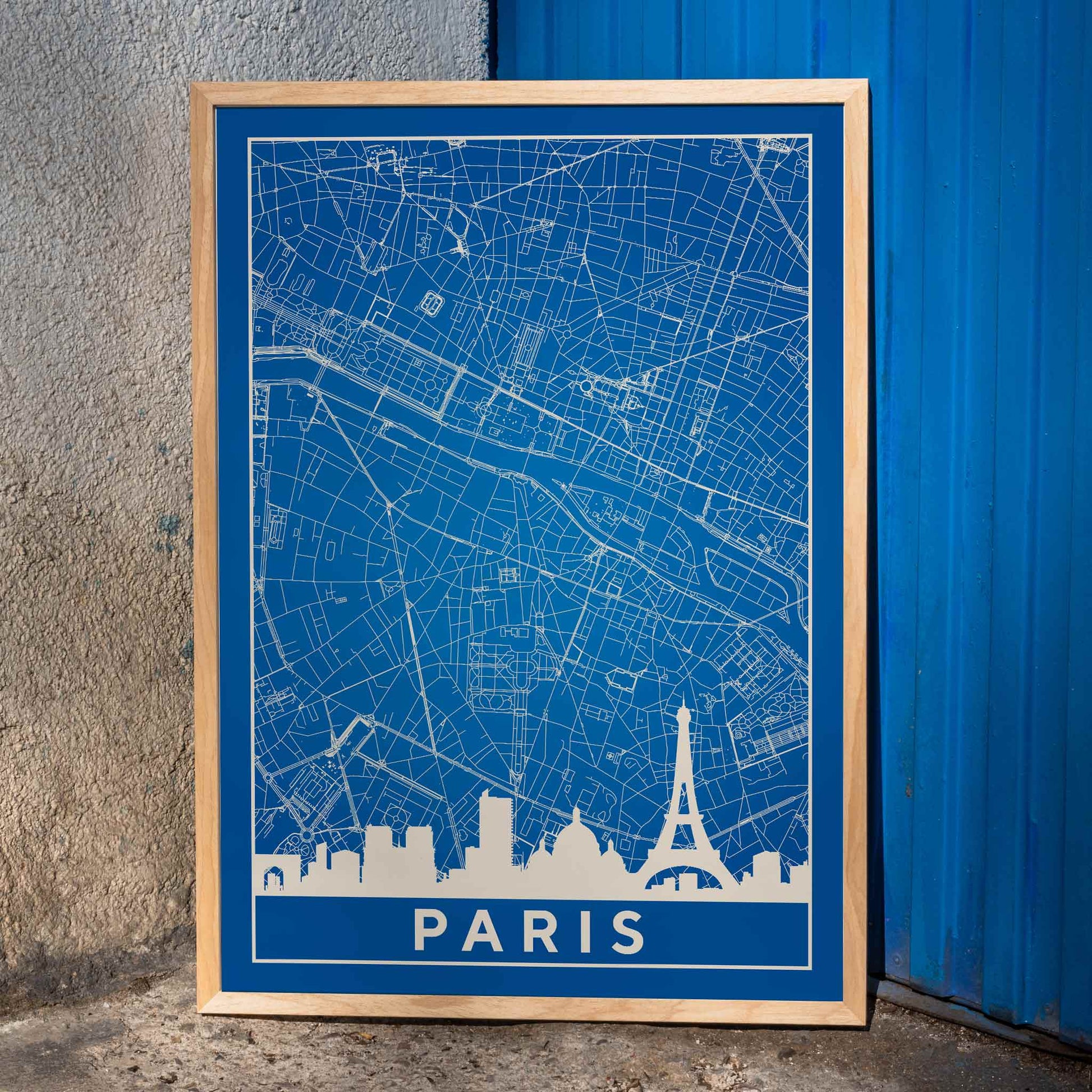 Minimalist Paris city map artwork and poster featuring detailed blue and white map with Eiffel Tower and prominent Paris landmarks, framed and displayed in home decor