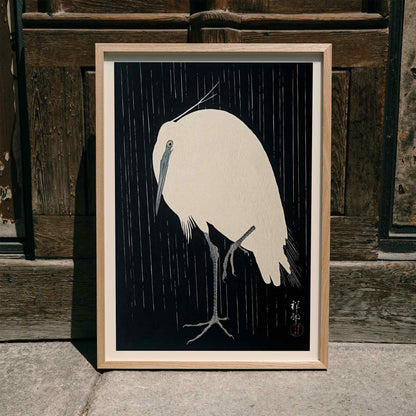 White egret standing in the rain art print poster with dark background by Ohara Koson, framed and displayed in modern living room decor