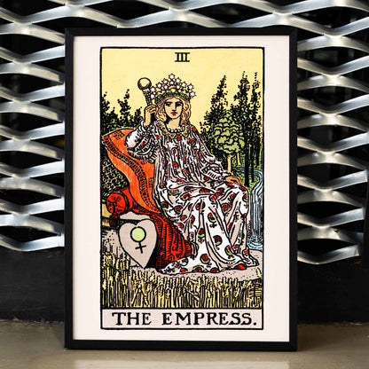 The Empress Tarot card by Rider Waite featuring a crowned woman seated on a throne in a lush natural setting holding a scepter with a crown of stars, framed and displayed in home decor