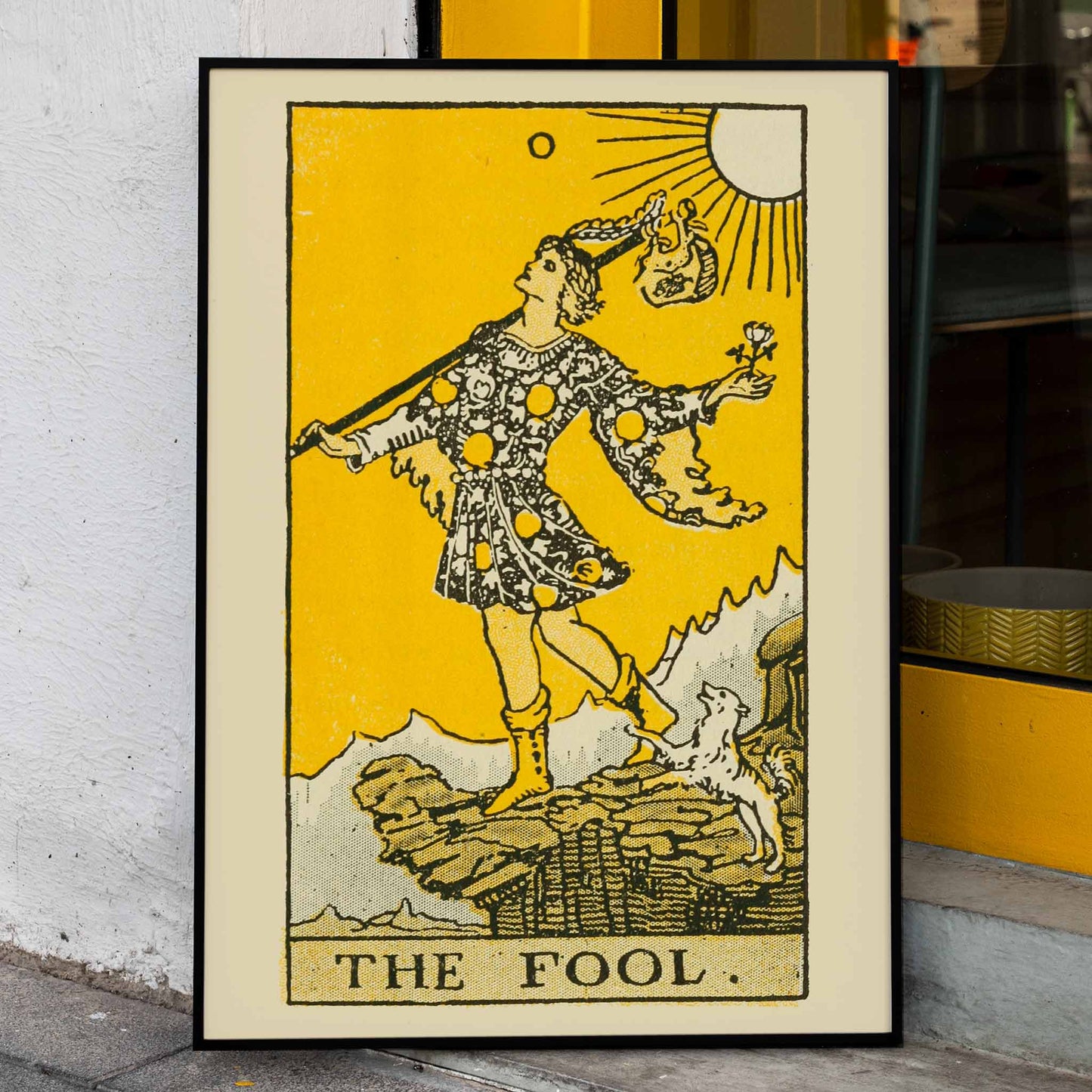 The Fool tarot card by Lauron William de Laurence showing a whimsical figure and dog on a cliff with a bright yellow background, framed and displayed in home decor