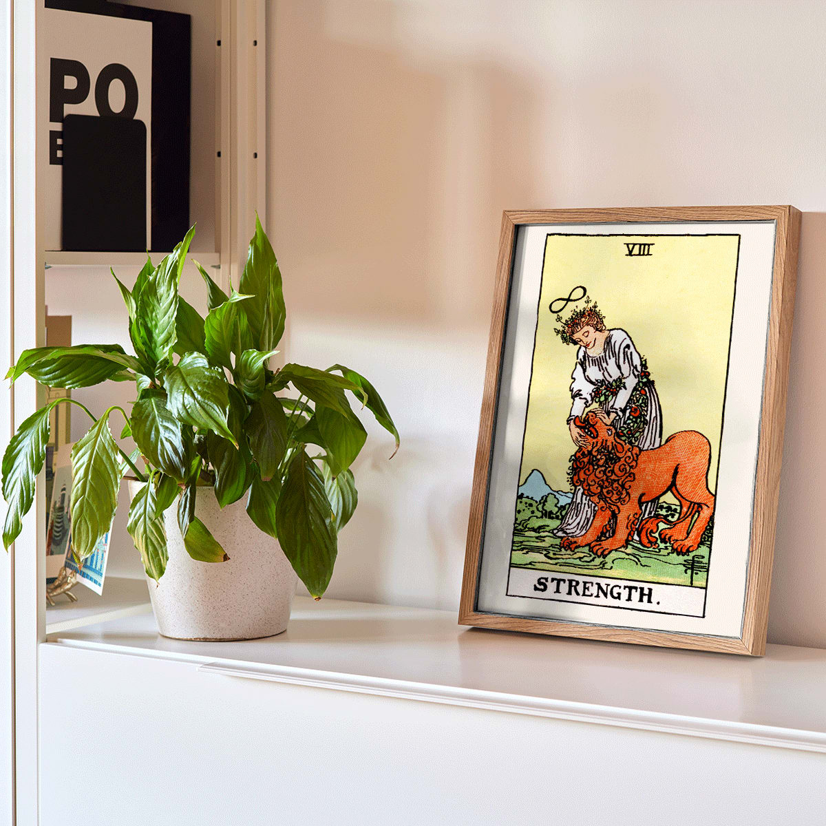 Tarot Strength card by Rider Waite showing a woman calming a lion with an infinity symbol above her head, framed and displayed in modern living room decor