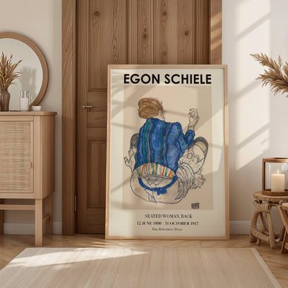 Egon Schiele Woman Seated Back exhibition poster showing a woman in a colorful garment sitting with her back turned artwork, framed and displayed in home decor